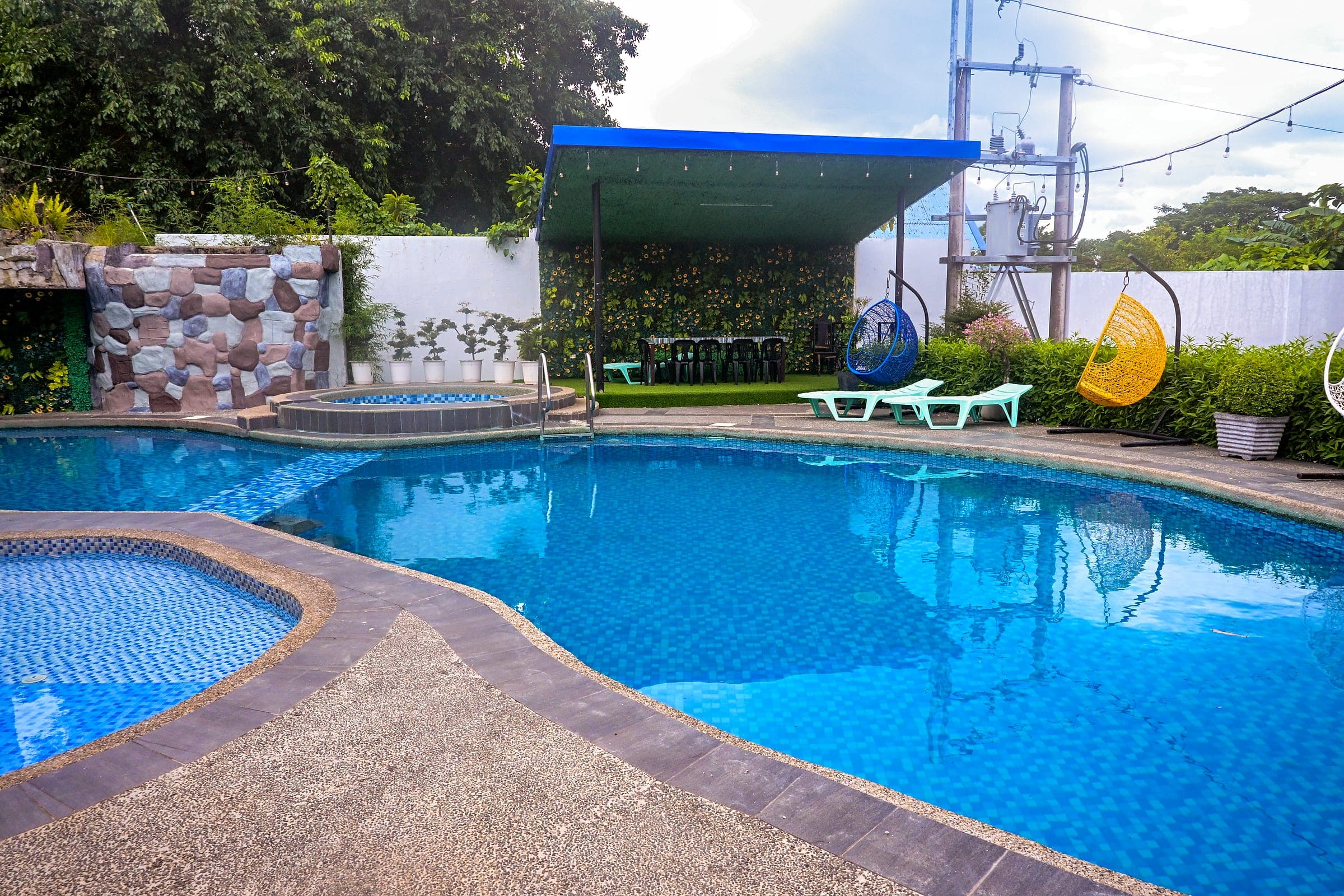 The swimming pool with the jacuzzi, sun loungers and covered seating alongside it